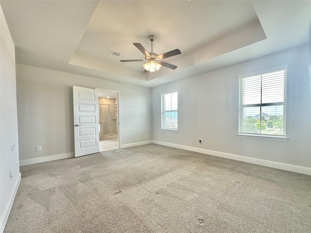 452 Long Beach Bay Dr, Katy, TX 77493 - unfurnished bedroom featuring a raised ceiling, light colored carpet, ensuite bathroom, and ceiling fan