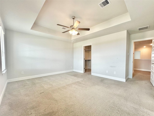 452 Long Beach Bay Dr, Katy, TX 77493 - unfurnished bedroom with a tray ceiling, light colored carpet, a walk in closet, and ceiling fan