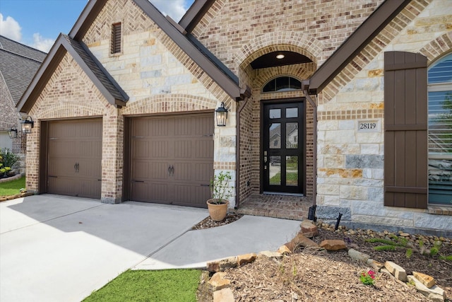 entrance to property with an attached garage, concrete driveway, and brick siding
