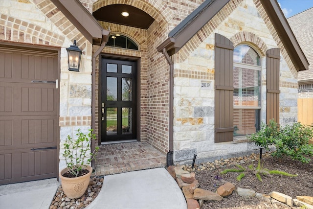 view of exterior entry featuring brick siding, a garage, french doors, and stone siding