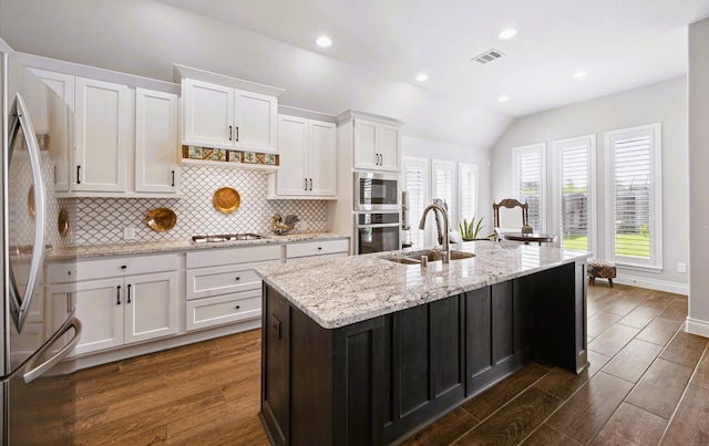 kitchen featuring visible vents, tasteful backsplash, a sink, white cabinets, and stainless steel appliances