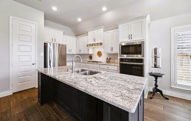 kitchen featuring decorative backsplash, dark wood-type flooring, white cabinetry, a sink, and stainless steel appliances