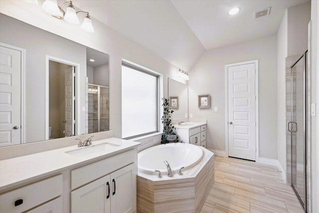 bathroom featuring a garden tub, visible vents, a shower stall, two vanities, and a sink