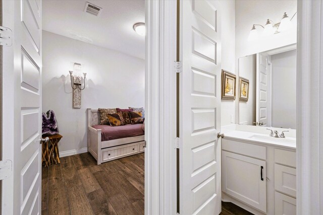 bathroom with baseboards, visible vents, wood finished floors, and vanity