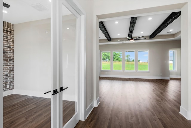 unfurnished living room with dark wood-type flooring, beam ceiling, and a ceiling fan