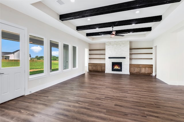 unfurnished living room with ceiling fan, dark wood-type flooring, a fireplace, baseboards, and beam ceiling