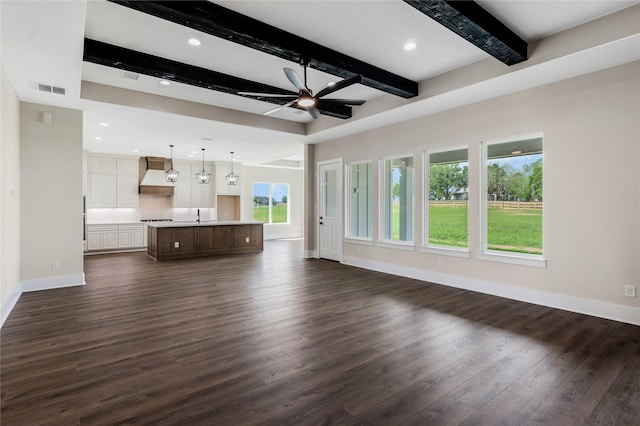 unfurnished living room with plenty of natural light, a ceiling fan, baseboards, and dark wood-style flooring