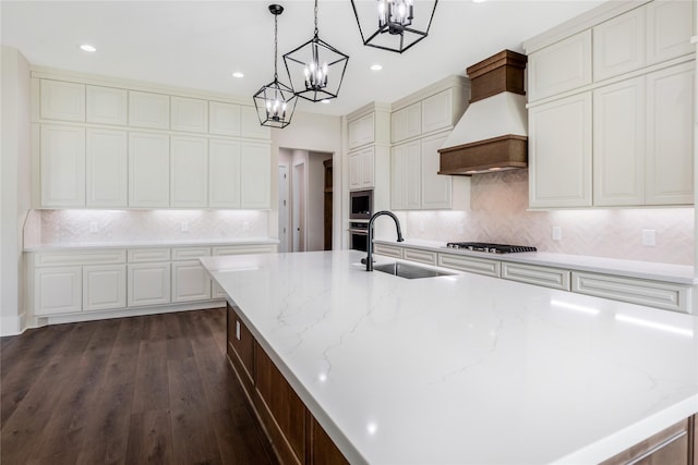 kitchen featuring a sink, tasteful backsplash, custom exhaust hood, a notable chandelier, and appliances with stainless steel finishes