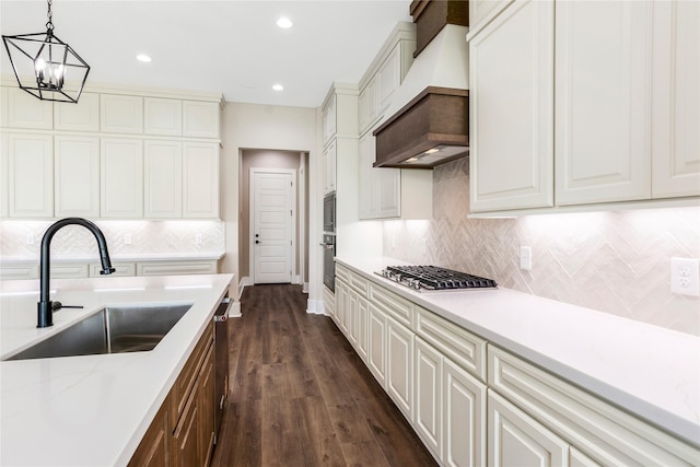 kitchen featuring a sink, dark wood-style flooring, decorative backsplash, appliances with stainless steel finishes, and premium range hood