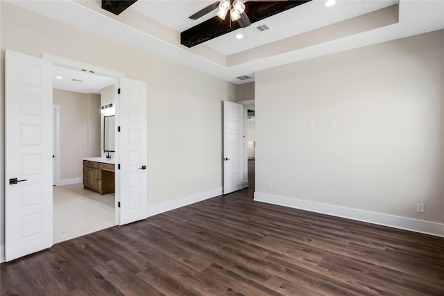 unfurnished bedroom with dark wood-style floors, a tray ceiling, baseboards, visible vents, and recessed lighting
