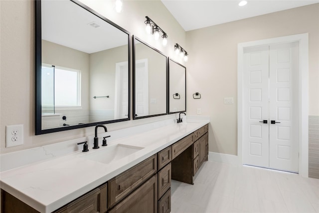bathroom featuring baseboards, visible vents, a sink, and double vanity