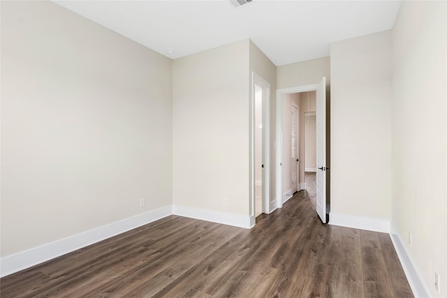spare room featuring visible vents, baseboards, and dark wood-style flooring