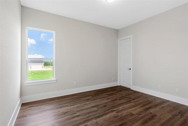 spare room featuring baseboards and dark wood finished floors