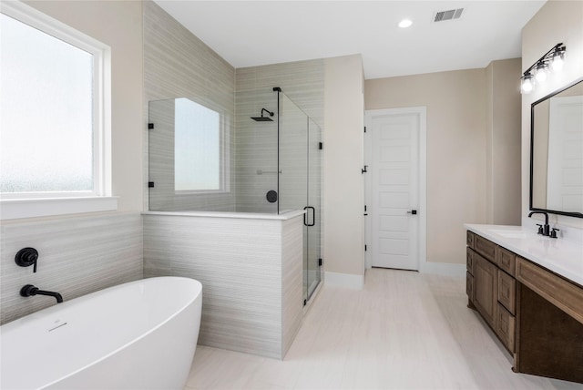 full bath with a shower stall, vanity, a soaking tub, baseboards, and visible vents