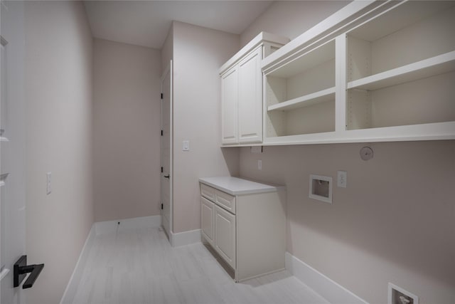 clothes washing area with hookup for a washing machine, baseboards, and cabinet space