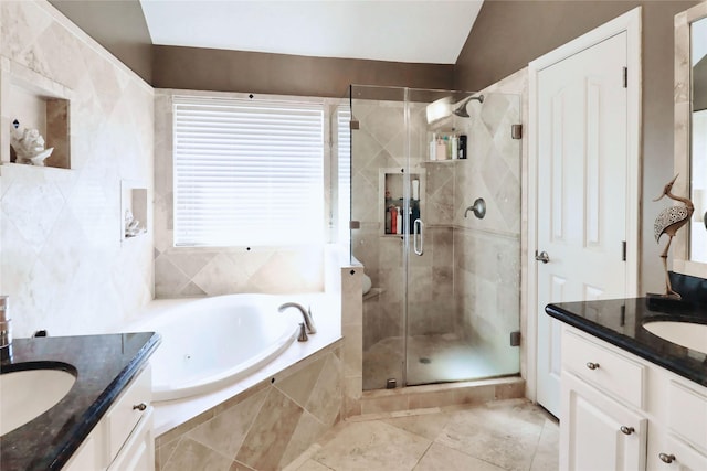 full bathroom featuring two vanities, a bath, a shower stall, tile patterned floors, and vaulted ceiling