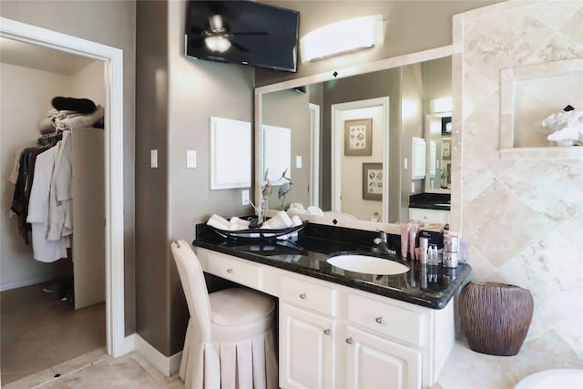 bathroom featuring vanity, baseboards, tile patterned flooring, and a spacious closet