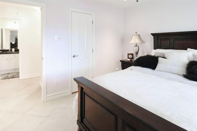 bedroom with light tile patterned flooring, connected bathroom, and baseboards
