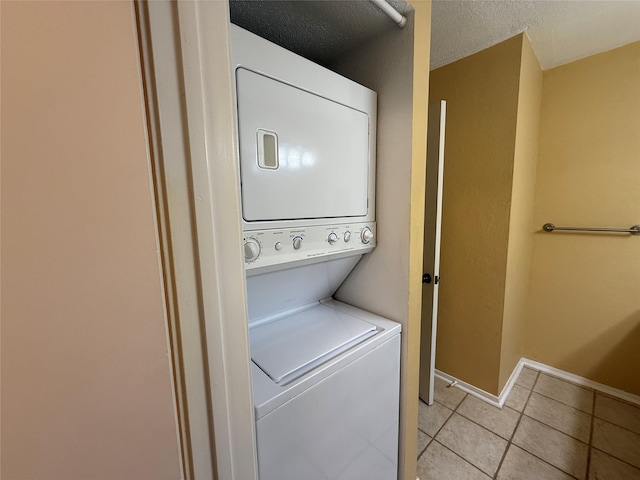 5711 Sugar Hill Dr Unit 62, Houston, TX 77057 - washroom featuring laundry area, light tile patterned flooring, stacked washer and dryer, baseboards, and a textured ceiling