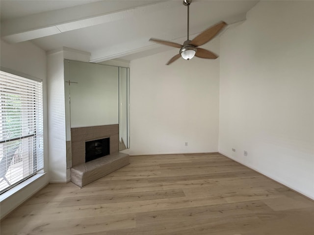 5711 Sugar Hill Dr Unit 62, Houston, TX 77057 - unfurnished living room featuring a fireplace with raised hearth, light wood finished floors, beam ceiling, and ceiling fan