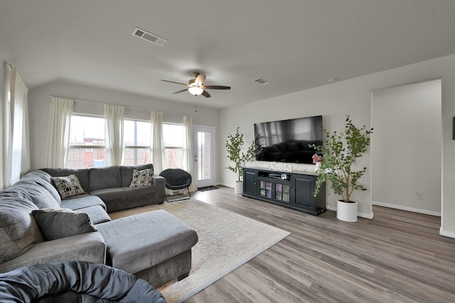 living room with light wood finished floors, baseboards, visible vents, and ceiling fan