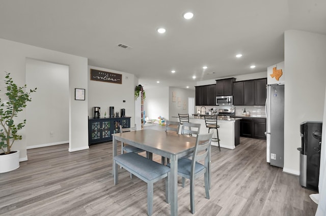 dining room with baseboards, light wood-style flooring, visible vents, and recessed lighting