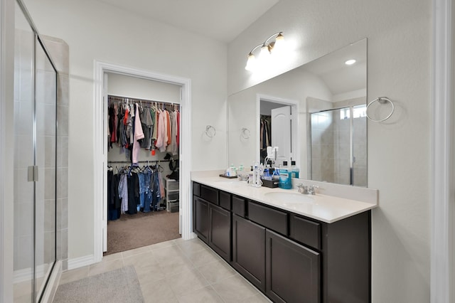 bathroom with a spacious closet, tile patterned flooring, double vanity, a sink, and a stall shower