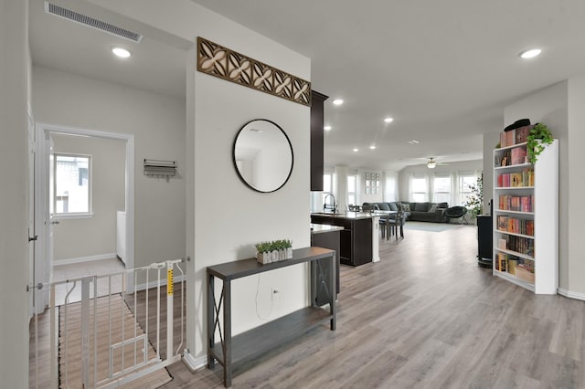 hall featuring light wood finished floors, visible vents, and recessed lighting