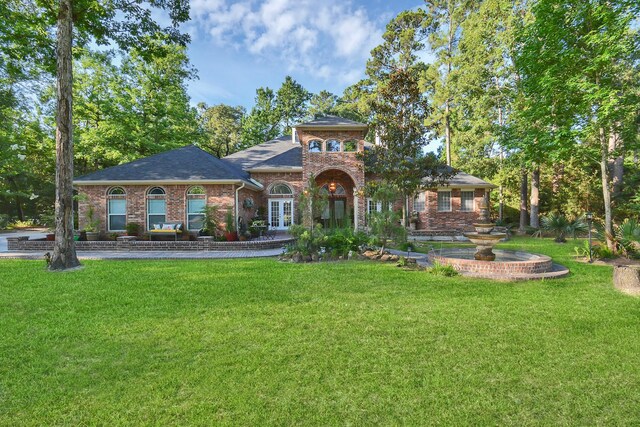 view of front of property with brick siding, french doors, and a front lawn