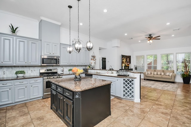 kitchen featuring stainless steel appliances, a peninsula, a sink, ceiling fan with notable chandelier, and crown molding