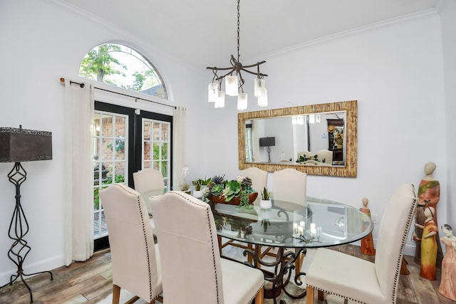 dining area featuring wood finished floors, ornamental molding, baseboards, and a notable chandelier
