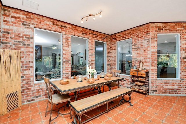 dining space with tile patterned floors, visible vents, and brick wall