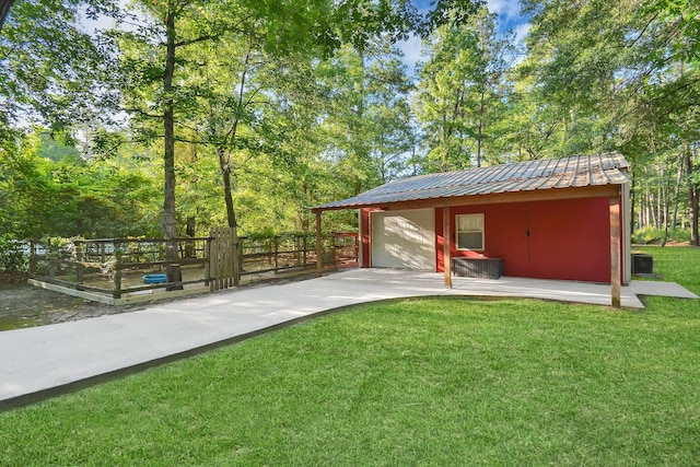 exterior space with an outdoor structure, concrete driveway, and fence