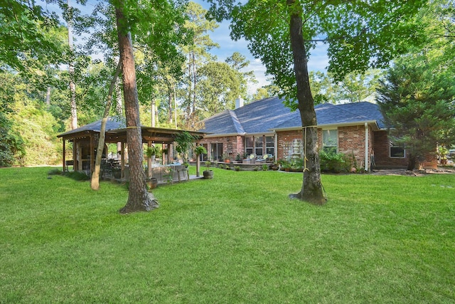 exterior space featuring brick siding, a front yard, and a patio