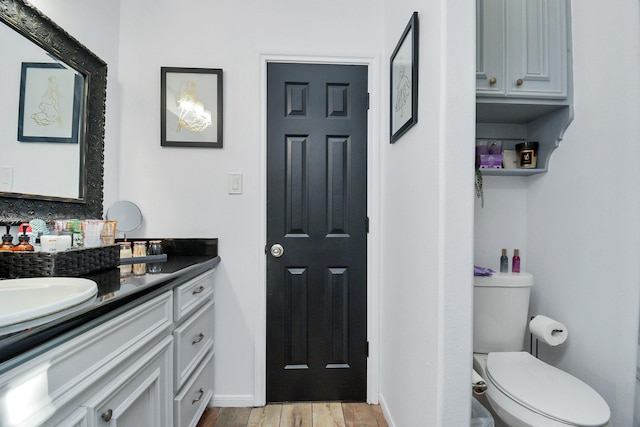 bathroom with wood finished floors, toilet, and vanity