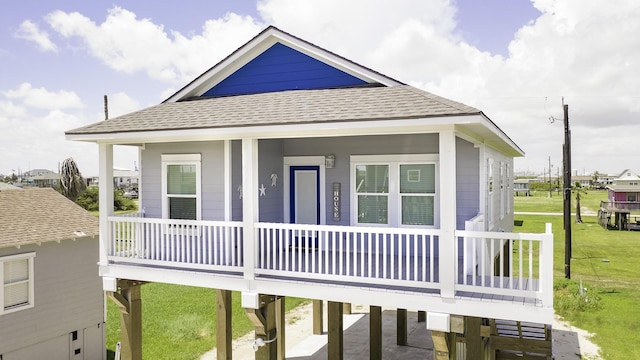 1014 Fort Velasco Dr, Surfside Beach, TX 77541 - view of front of house with a porch, a front lawn, roof with shingles, and a carport