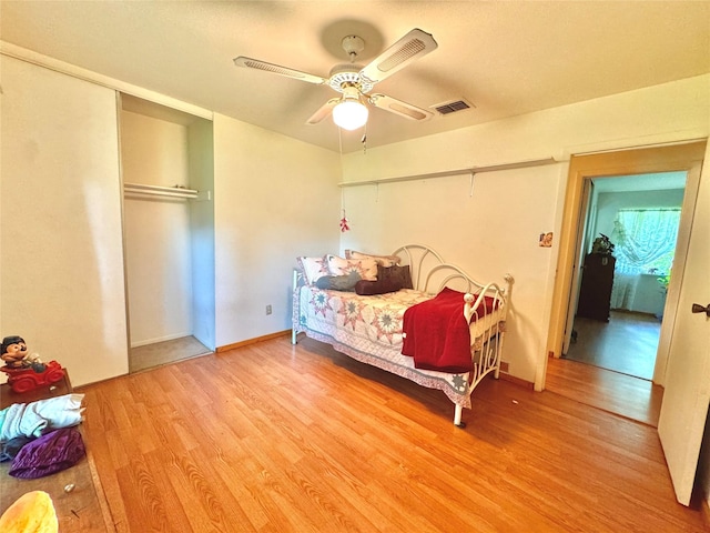 bedroom with wood finished floors, visible vents, a closet, and ceiling fan