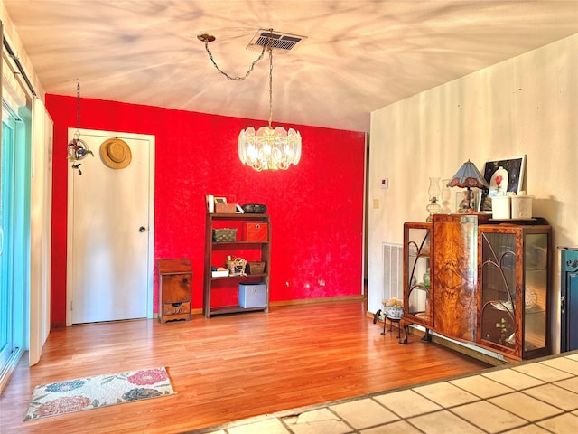 dining room featuring wood finished floors, visible vents, and a chandelier