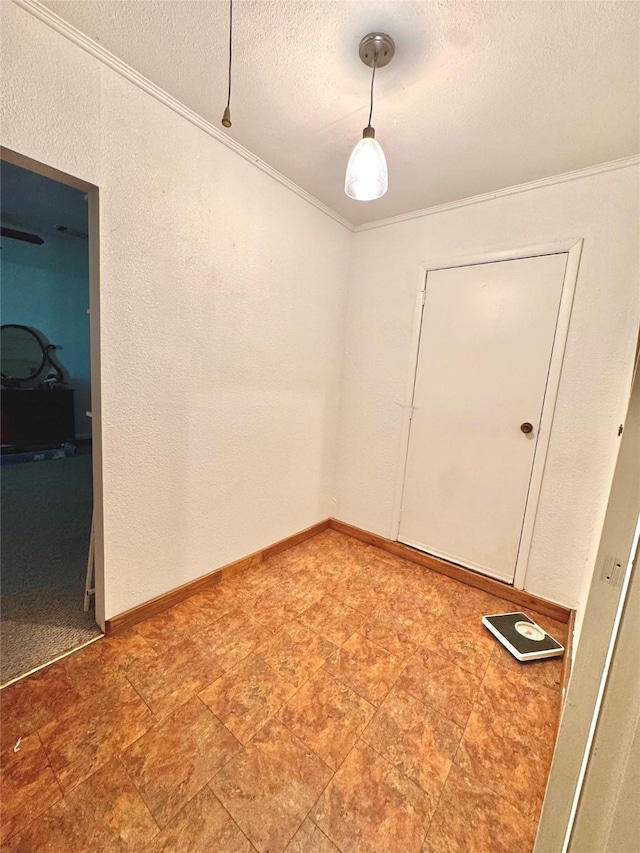 unfurnished room featuring stone finish floor, a textured wall, a textured ceiling, and ornamental molding