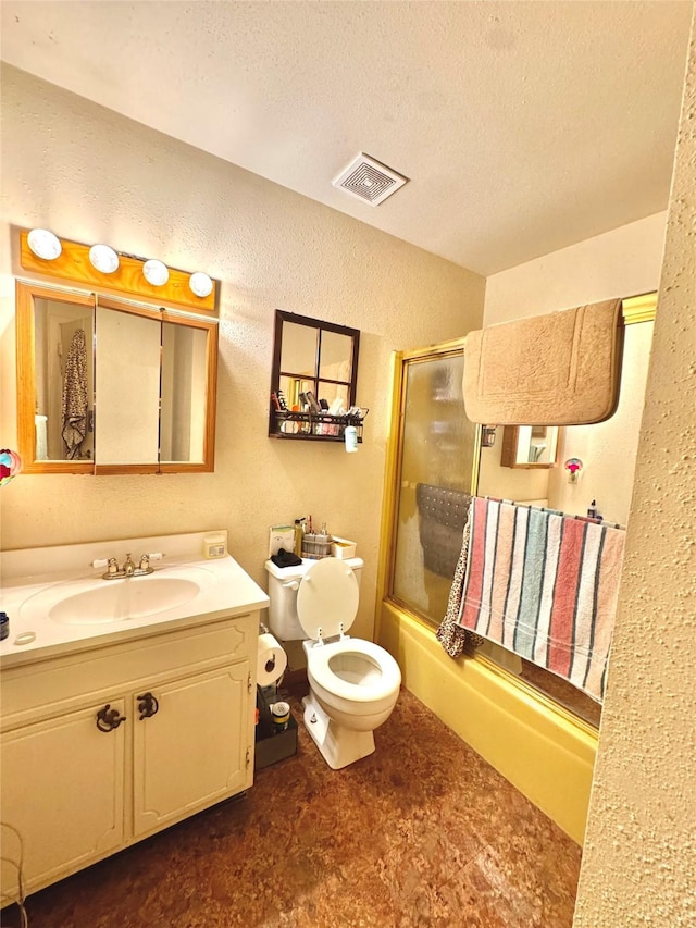 bathroom featuring a textured ceiling, combined bath / shower with glass door, vanity, a textured wall, and visible vents