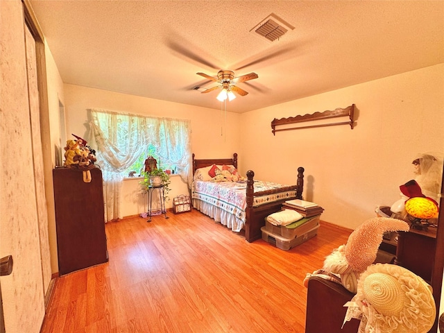 bedroom featuring ceiling fan, wood finished floors, visible vents, and a textured ceiling
