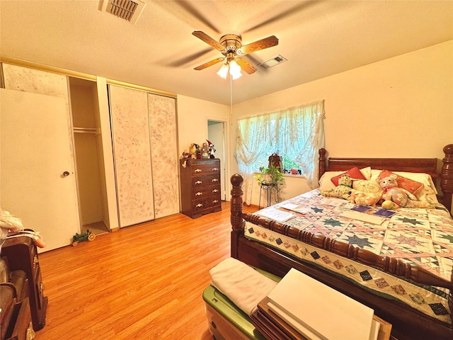 bedroom with two closets, ceiling fan, light wood finished floors, and visible vents