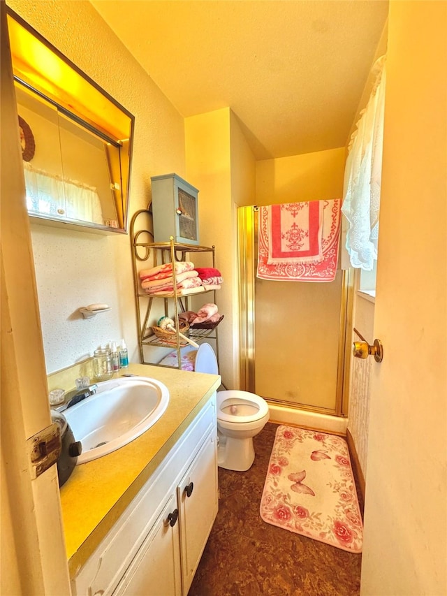 bathroom with vanity, a shower stall, and toilet
