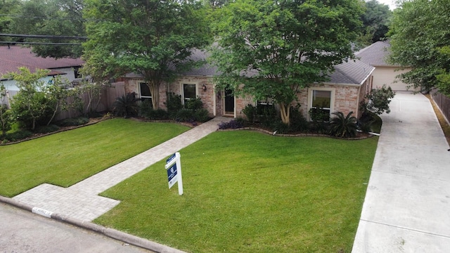 view of front of home with a front lawn, concrete driveway, fence, brick siding, and a shingled roof