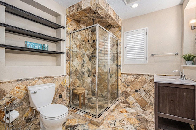 bathroom featuring a textured ceiling, toilet, tile walls, a shower stall, and vanity