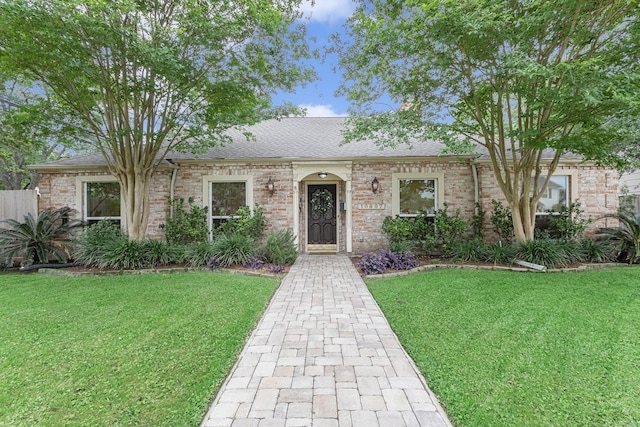 view of front of home featuring brick siding, a shingled roof, and a front lawn