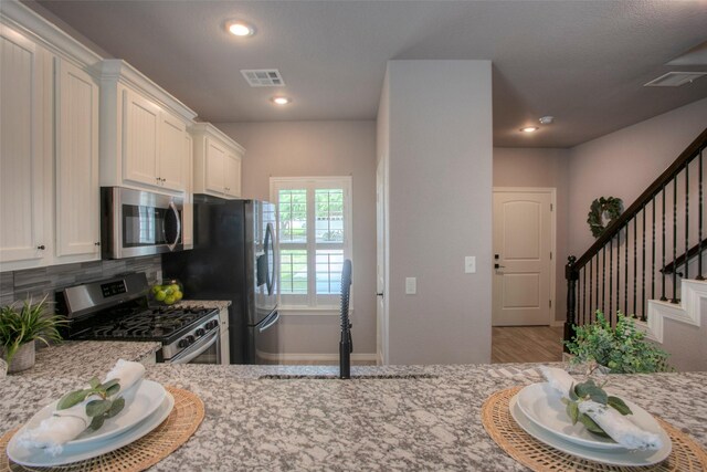 279 Capetown, Conroe, TX 77356 - kitchen featuring stainless steel appliances, light stone counters, white cabinets, backsplash, and recessed lighting