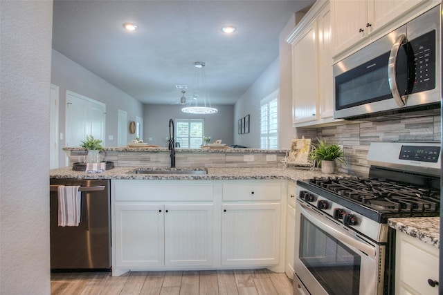 279 Capetown, Conroe, TX 77356 - kitchen featuring stainless steel appliances, a sink, light wood-style floors, tasteful backsplash, and white cabinets