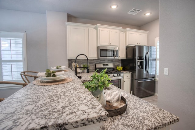 279 Capetown, Conroe, TX 77356 - kitchen with appliances with stainless steel finishes, decorative backsplash, white cabinetry, plenty of natural light, and recessed lighting