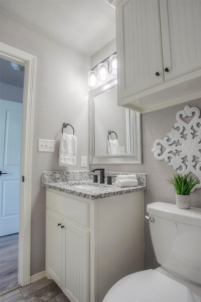 279 Capetown, Conroe, TX 77356 - half bath with vanity, toilet, wood finished floors, and a textured wall